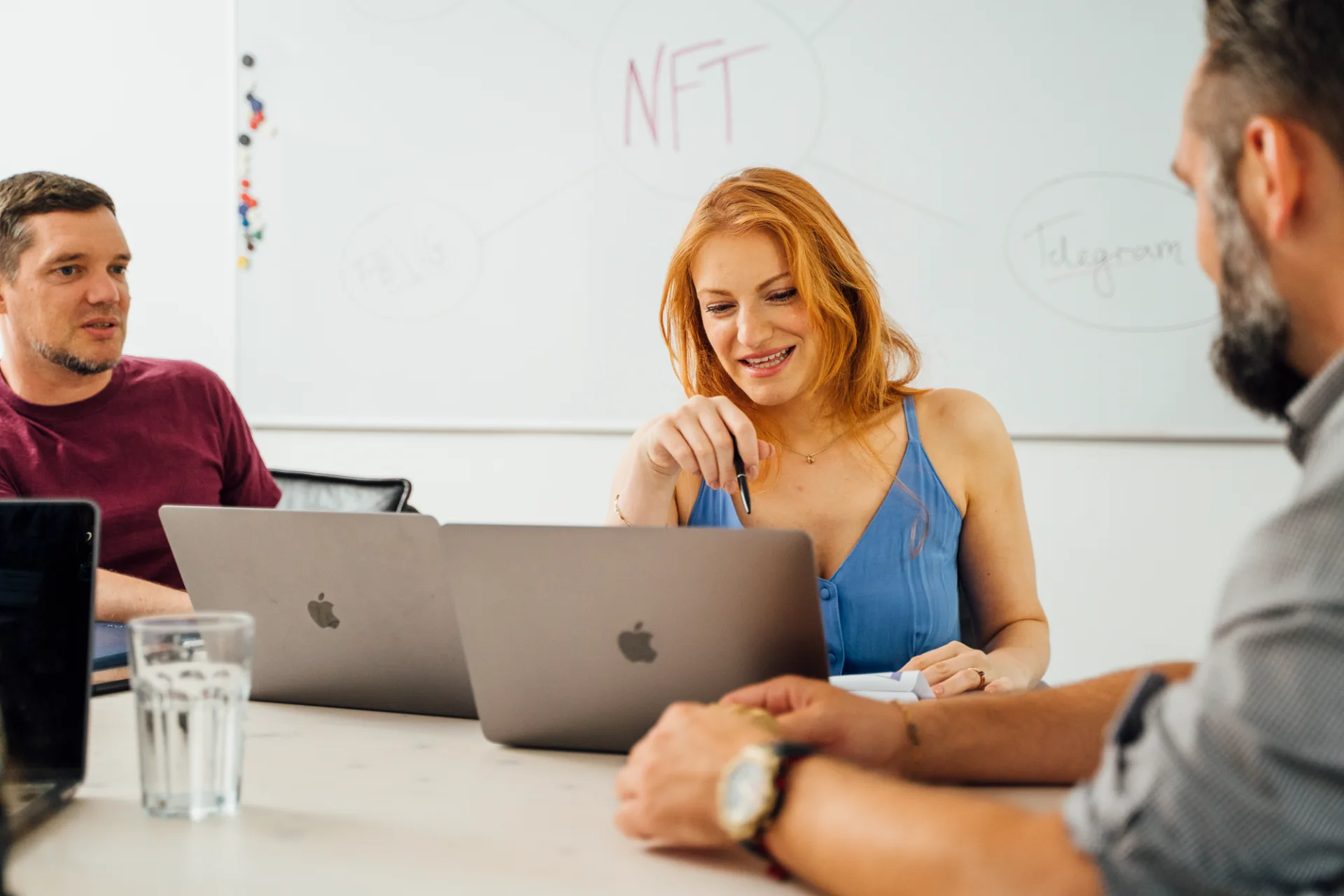 Drei Personen besprechen an einem Tisch einen digitalen Arbeitsablauf